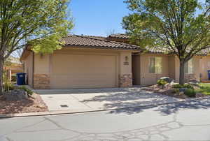 View of front of home featuring stone siding, an attached garage, stucco siding, concrete driveway, and a tiled roof