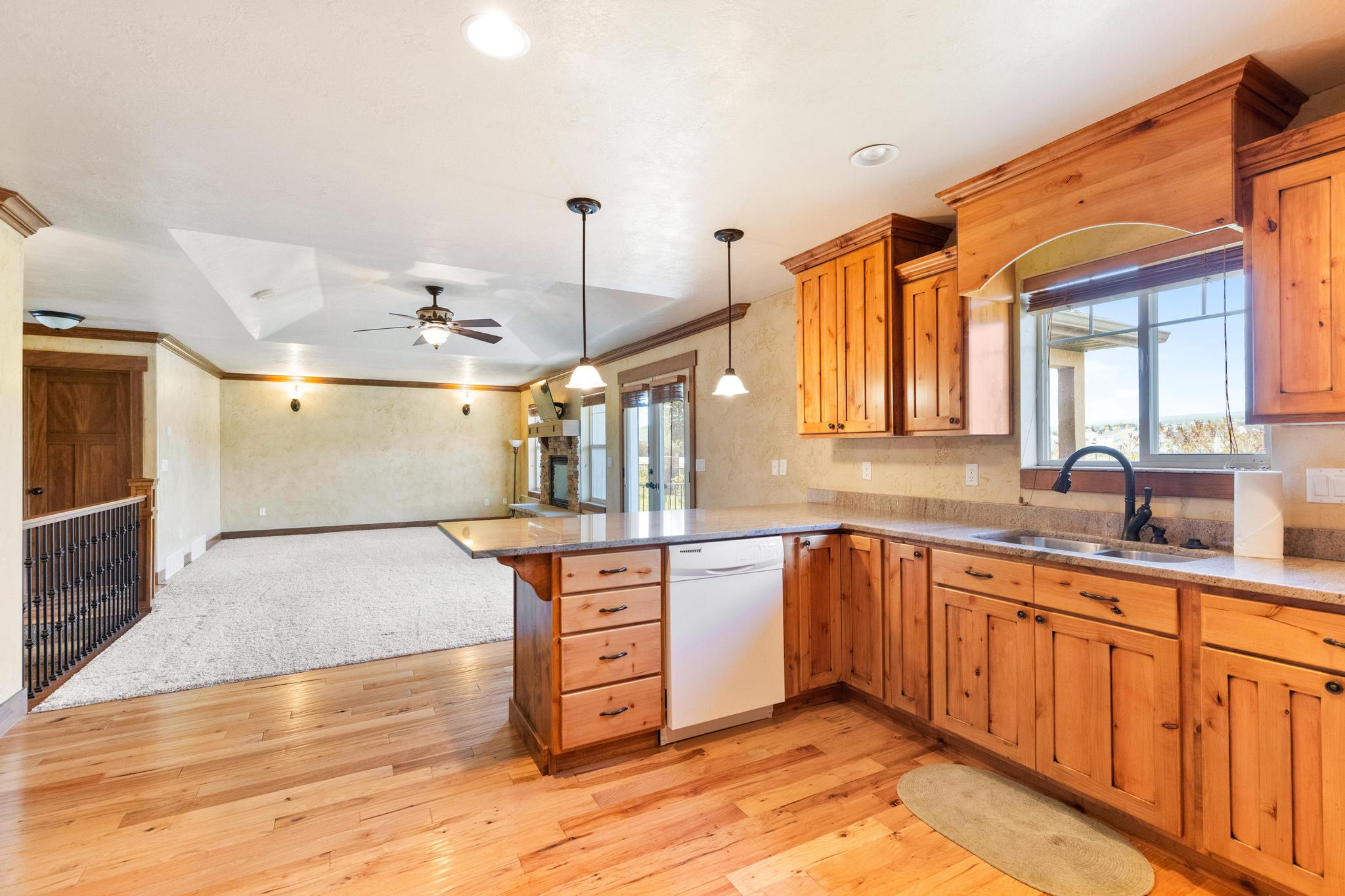 Kitchen featuring white dishwasher, a peninsula, open floor plan, light wood-style flooring, and a ceiling fan