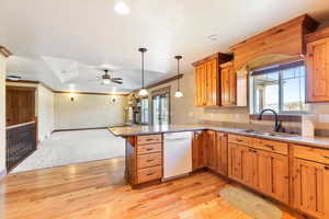 Kitchen featuring white dishwasher, a peninsula, open floor plan, light wood-style flooring, and a ceiling fan