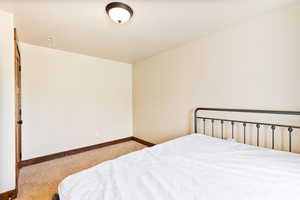 Bedroom with light colored carpet and baseboards