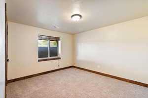 Spare room with baseboards and light carpet