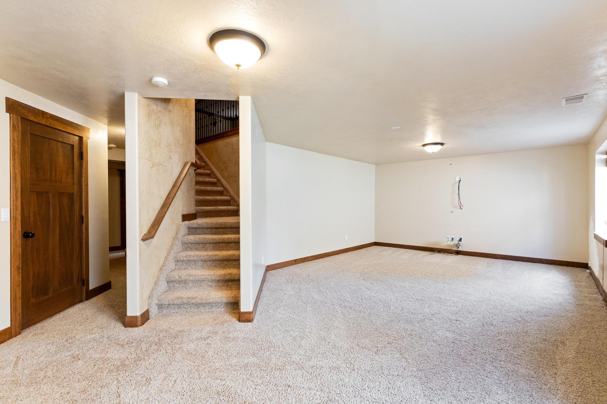 Finished basement featuring light colored carpet and stairs