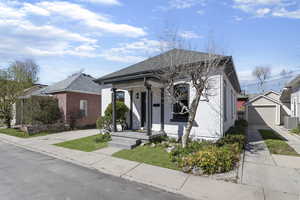 View of front of property with a porch, an outdoor structure, a detached garage, and a front yard