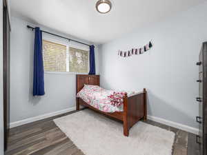 Bedroom with baseboards and dark wood-type flooring