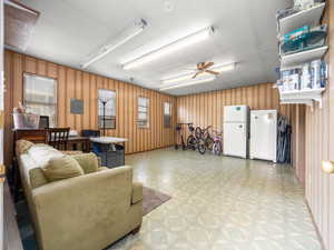 Living area featuring a ceiling fan, light floors, and electric panel