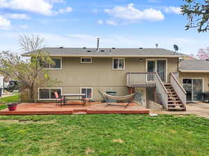 Rear view of property featuring a deck, a lawn, and a shingled roof