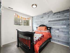 Carpeted bedroom with wooden walls and baseboards