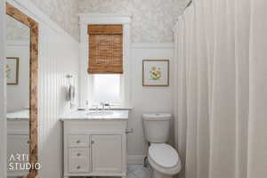 Full bath featuring vanity, a shower with shower curtain, and wallpapered walls