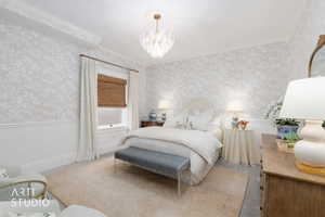 Bedroom featuring carpet, hanging lights, ornamental molding, a wainscoted wall, and wallpapered walls