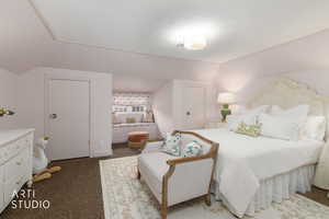 Bedroom with dark carpet and vaulted ceiling