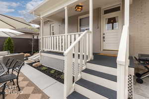 View of exterior entry featuring brick siding and covered porch