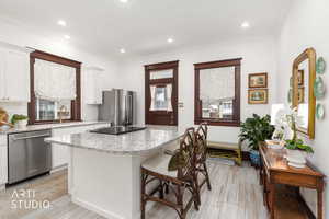 Kitchen with light stone countertops, white cabinetry, stainless steel appliances, a center island, and recessed lighting