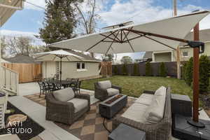 Fenced backyard with a fire pit, an outdoor living / dining area, a patio, and an outbuilding