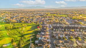 Aerial perspective of suburban area featuring a mountainous background and a local golf course