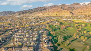 Aerial perspective of suburban area featuring a mountain backdrop and a golf course