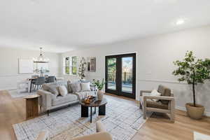 Living area featuring light wood-style flooring, french doors, and hanging lights