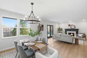 Dining room with light wood-type flooring, a high end fireplace, and a chandelier