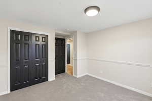Unfurnished bedroom featuring light carpet and a closet