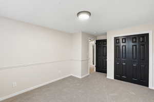 Unfurnished bedroom with light carpet and a closet