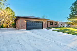 View of front of home with an attached garage, brick siding, driveway, and a shingled roof