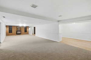 Finished below grade area featuring a wood stove and light colored carpet