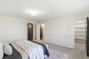 Bedroom featuring a spacious closet and light colored carpet
