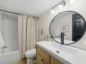 Full bathroom featuring vanity, shower / tub combo, and a textured ceiling