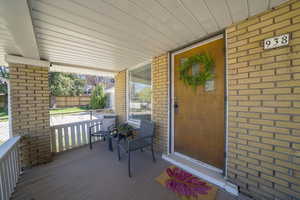Doorway to property with brick siding and a deck
