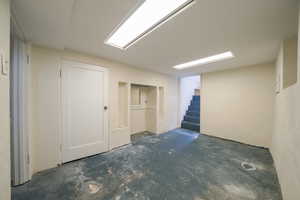 Finished below grade area featuring a textured wall and stairway