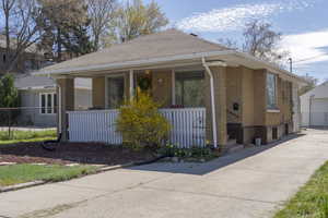 View of front facade featuring an outbuilding, a detached garage, brick siding, and a porch