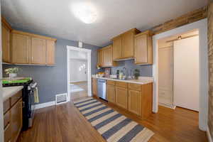 Kitchen featuring light countertops, stainless steel appliances, dark wood-type flooring, and wood finish cabinets