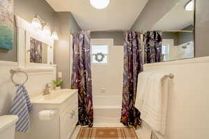 Bathroom featuring vanity and shower / bath combination with curtain