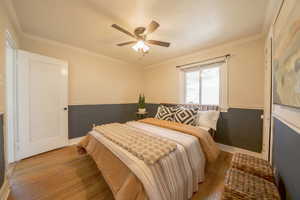 Bedroom with ornamental molding, hardwood / wood-style flooring, and ceiling fan