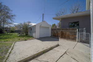 Detached garage featuring concrete driveway and a gate