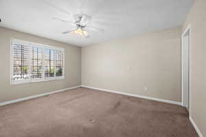 Carpeted empty room featuring a ceiling fan and a textured ceiling