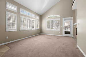 Unfurnished living room featuring lofted ceiling, carpet floors, and a glass covered fireplace