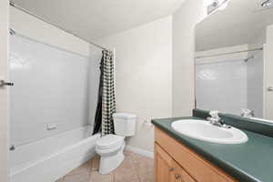 Bathroom featuring vanity, light tile patterned floors, shower / bath combination with curtain, and a textured ceiling