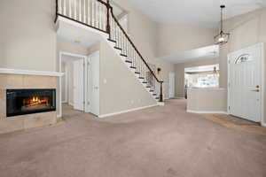 Entrance foyer featuring light carpet, a tile fireplace, lofted ceiling, and hanging lights