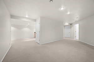 Below grade area with light colored carpet and recessed lighting