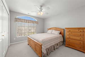 Bedroom with a closet, a ceiling fan, and light colored carpet