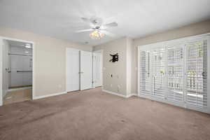 Unfurnished bedroom with access to exterior, light carpet, ensuite bath, and ceiling fan