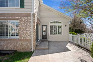 View of exterior entry featuring brick siding and a patio area