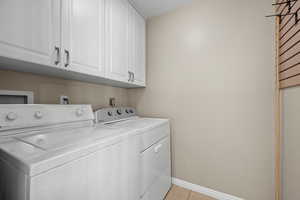 Laundry area with cabinet space, washing machine and clothes dryer, and light tile patterned floors
