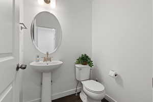 Main floor half bathroom featuring pedestal sink, stylish mirror, and LVP flooring