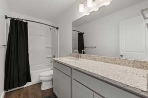 Bathroom featuring vanity, shower / bath combo, and dark wood finished floors