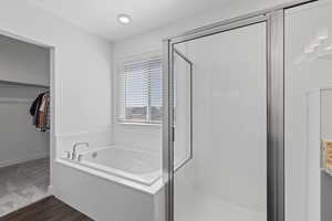Primary ensuite bathroom featuring LVP flooring, a separate tub and shower, and walk-in closet