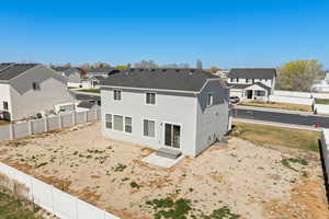 Rear view of property featuring large backyard, open patio area, vinyl fencing, and partial landscaping
