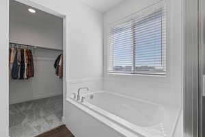 Primary ensuite bathroom featuring LVP flooring, a separate tub and shower, and walk-in closet