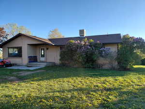 View of front of home featuring brick siding, a front yard, a shingled roof, and a patio area