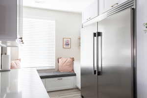 Kitchen featuring built in refrigerator, white cabinets, light wood-type flooring, and open shelves